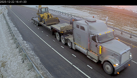 Roadside camera capture of the flatbed truck and end loader involved in the documented over-height incident
