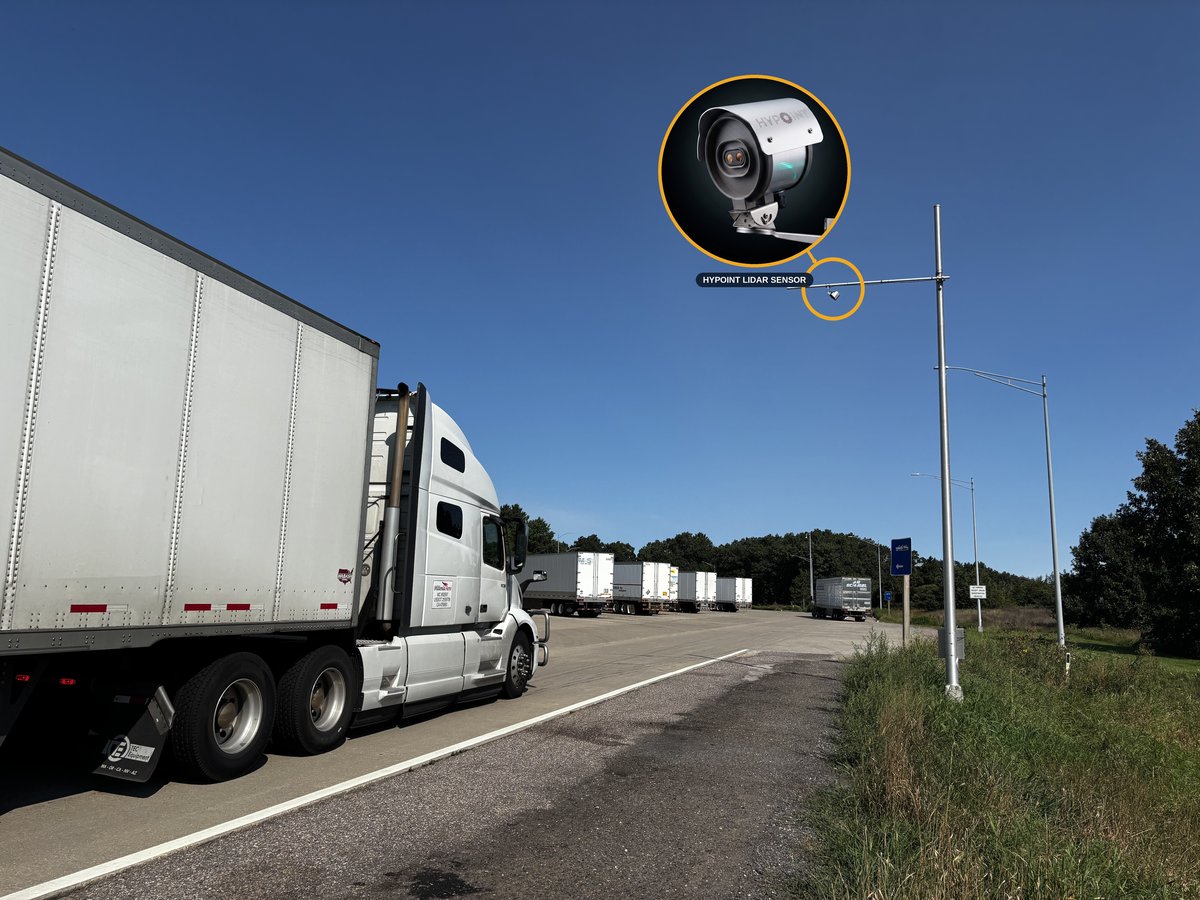 Pole-mounted Kingfisher LiDAR sensor overlooking a truck parking facility entrance, with a close-up callout of the sensor unit